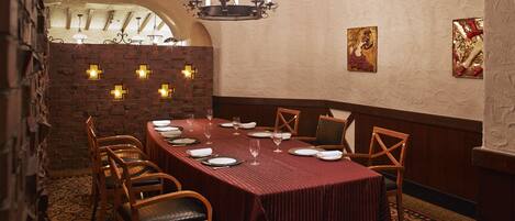 A dining area with a long table set for six, surrounded by wooden chairs.