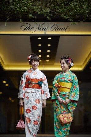 Dos personas vestidas con kimonos tradicionales japoneses posan frente a un edificio con un letrero que dice "The New Otani".