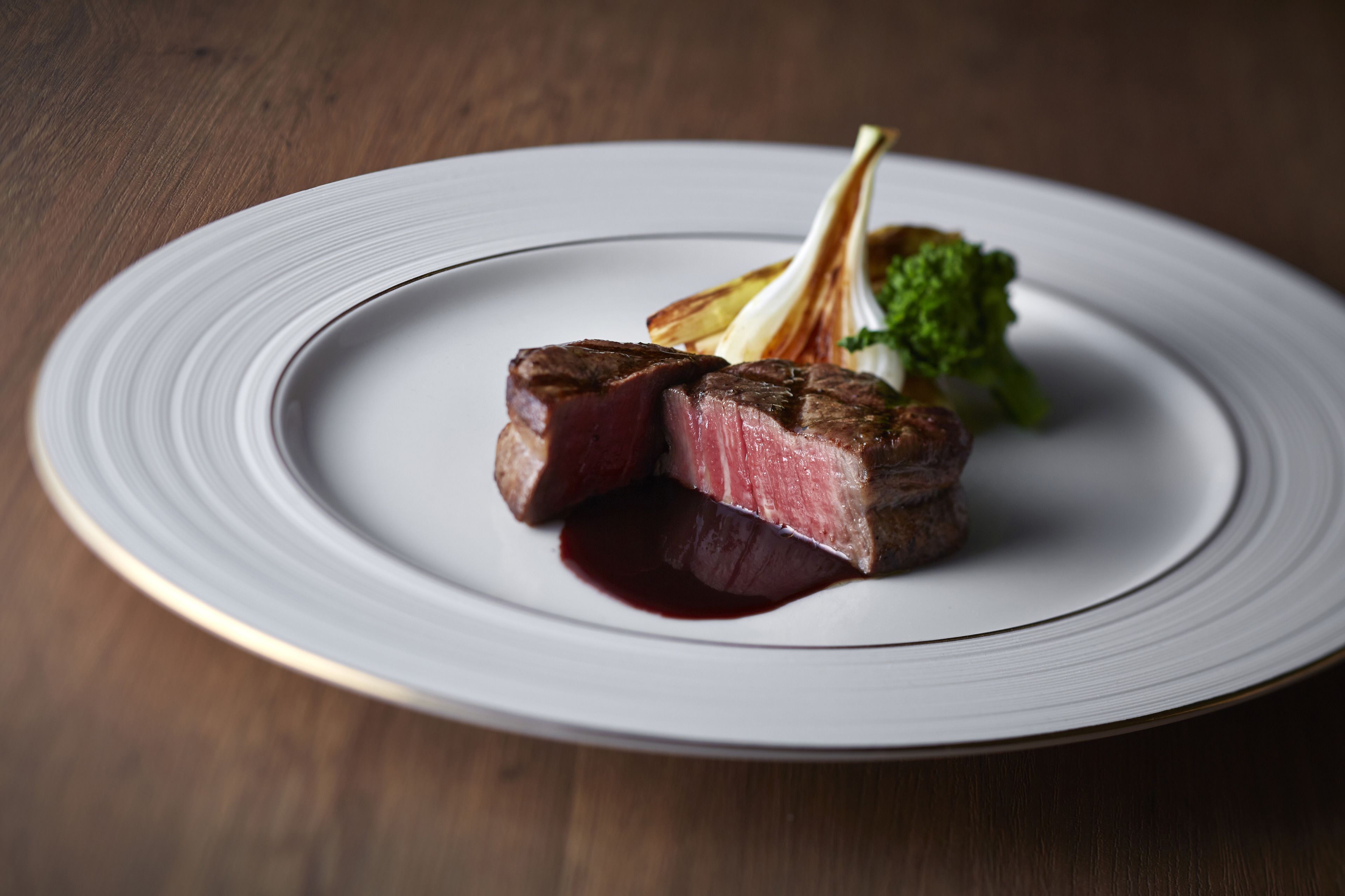 A plate with a steak, vegetables, and sauce.