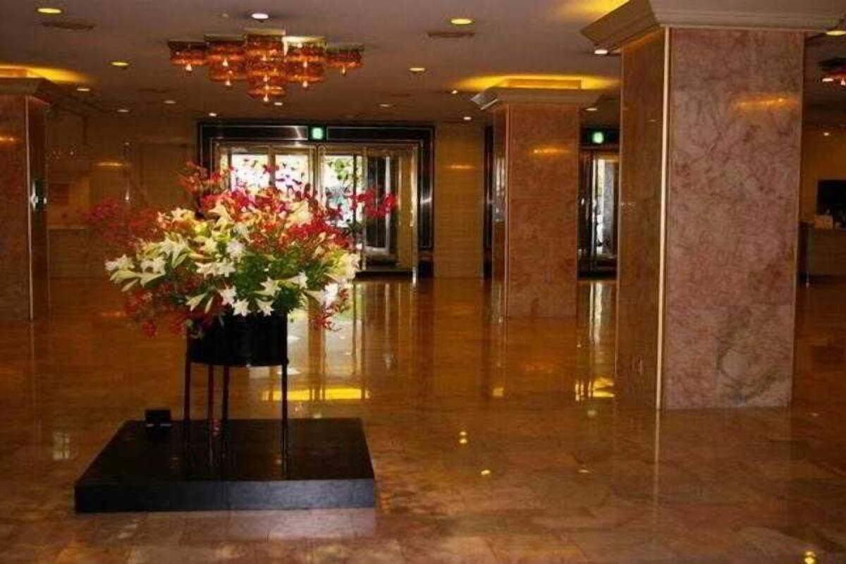 Un hall d’hôtel doté d’un sol en marbre, d’une composition florale centrale et d’un lustre moderne.