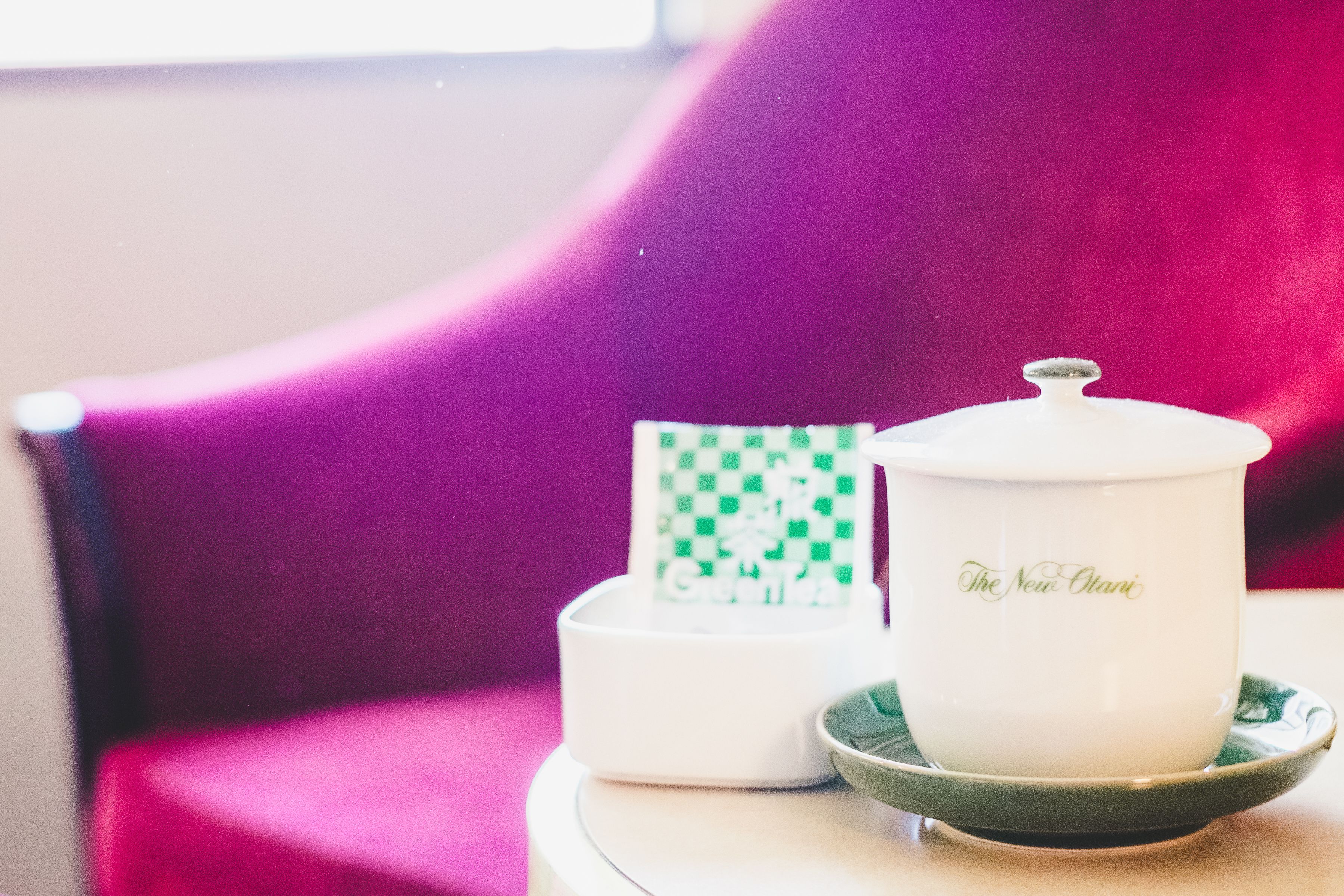 A white ceramic cup with a lid and saucer on a small round table.