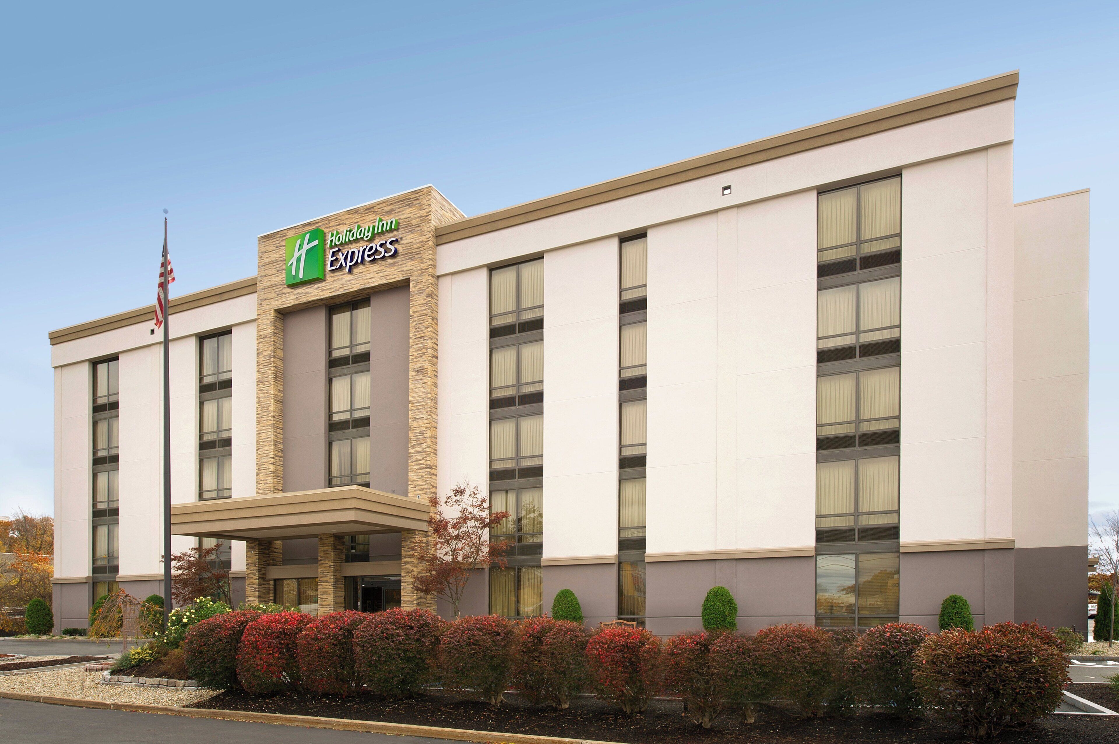 A Holiday Inn Express building with a stone facade, large windows, and a flagpole.