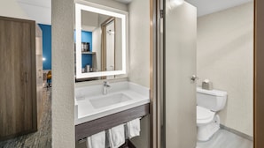 A modern bathroom with a large mirror, white sink, and a toilet.