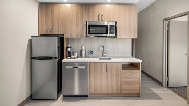 A modern kitchen with stainless steel appliances, wooden cabinets, and a white countertop.