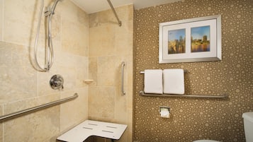 A bathroom with a shower, grab bars, a toilet, and a wall-mounted sink.