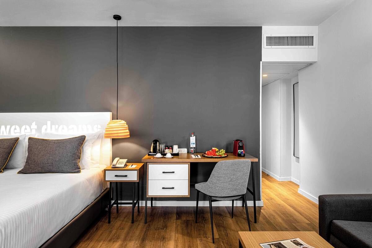Une chambre d’hôtel moderne équipée d’un lit, d’un bureau, d’une chaise et d’une petite table.