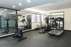 Un gimnasio con cintas de correr, elípticas y un espejo grande.
