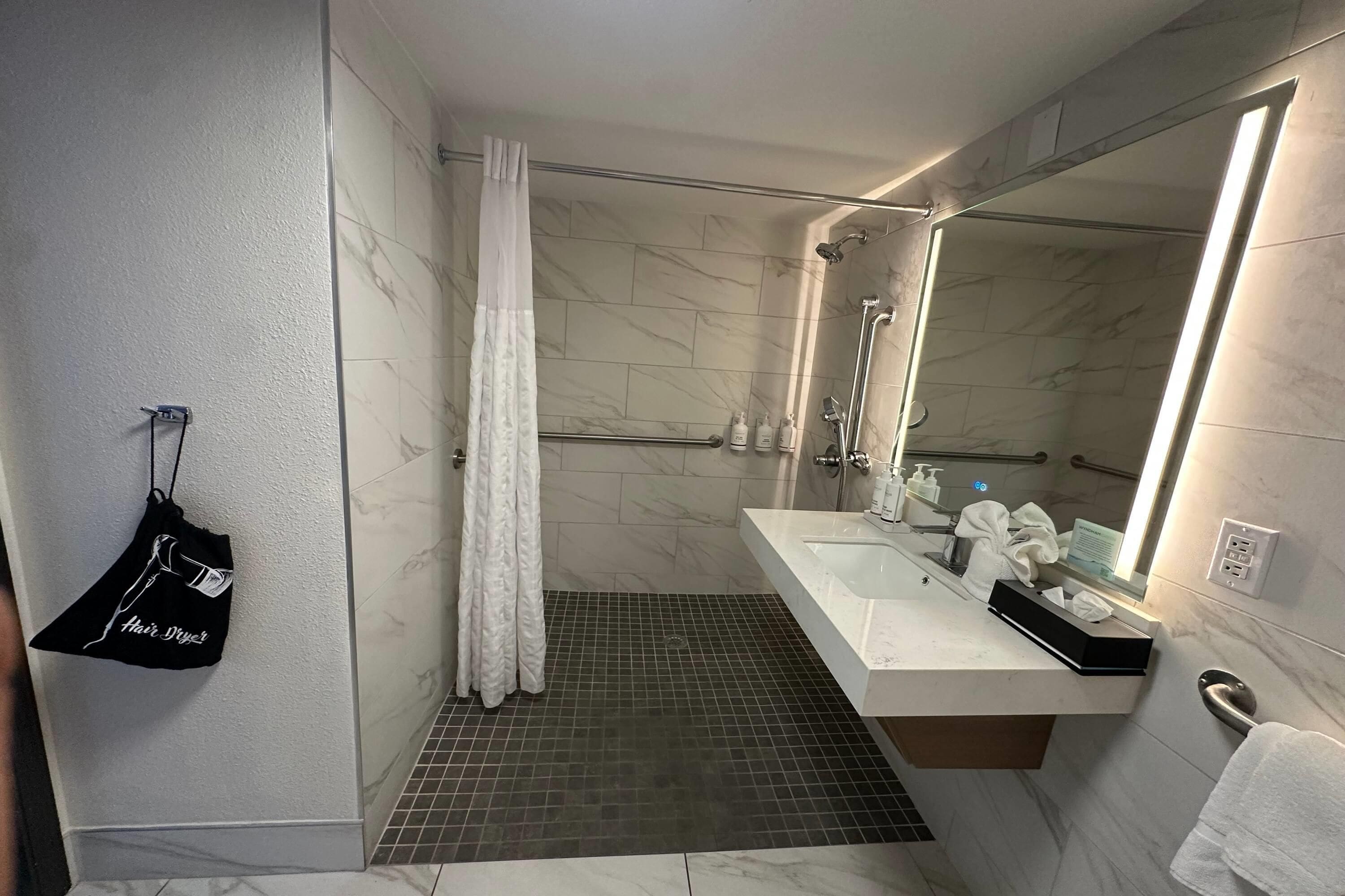 Un baño moderno con ducha, lavamanos y espejo.