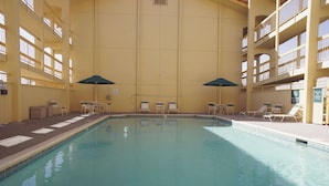 An indoor swimming pool with multiple levels of balconies, sun loungers, and umbrellas. - La Quinta Inn by Wyndham Albuquerque Airport (Albuquerque)