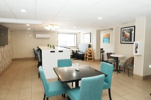 Una habitación de hotel moderna con zona de comedor, kitchenette y un ventanal grande.