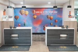 Un área de recepción con un mural de globos aerostáticos y un letrero que dice 'despierta del lado soleado Albuquerque, Nuevo México'.