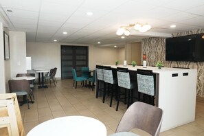 A modern hotel lobby with a reception desk, bar stools, and a flat-screen TV mounted on the wall. - La Quinta Inn by Wyndham Albuquerque Airport (Albuquerque)