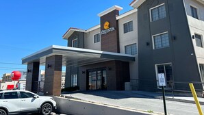 A hotel with a modern design, featuring a prominent 'La Quinta' sign, a covered entrance, and a 'Veteran Parking' sign. - La Quinta Inn by Wyndham Albuquerque Airport (Albuquerque)