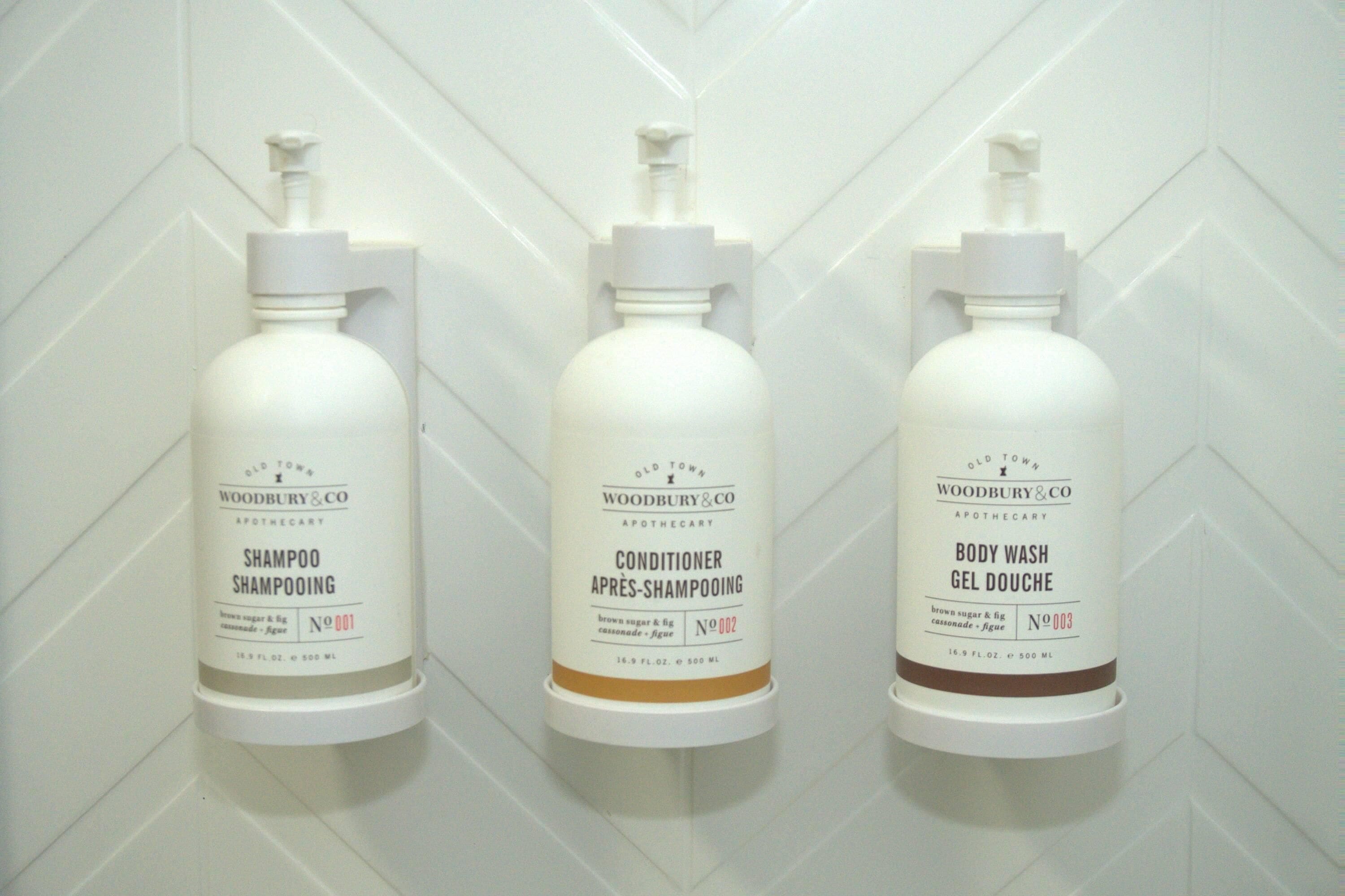Three bottles of Old Town Woodbury & Co. products: shampoo, conditioner, and body wash, each with a pump dispenser.