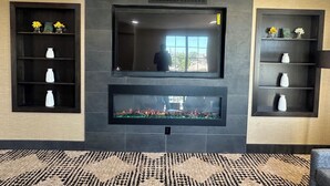 A modern interior with a fireplace, decorative shelves, and a patterned carpet. - La Quinta Inn by Wyndham Albuquerque Airport (Albuquerque)