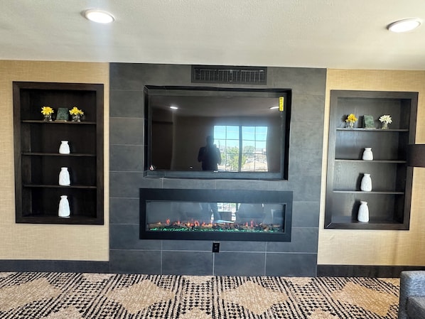 A modern interior with a fireplace, decorative shelves, and a patterned carpet. - La Quinta Inn by Wyndham Albuquerque Airport (Albuquerque)