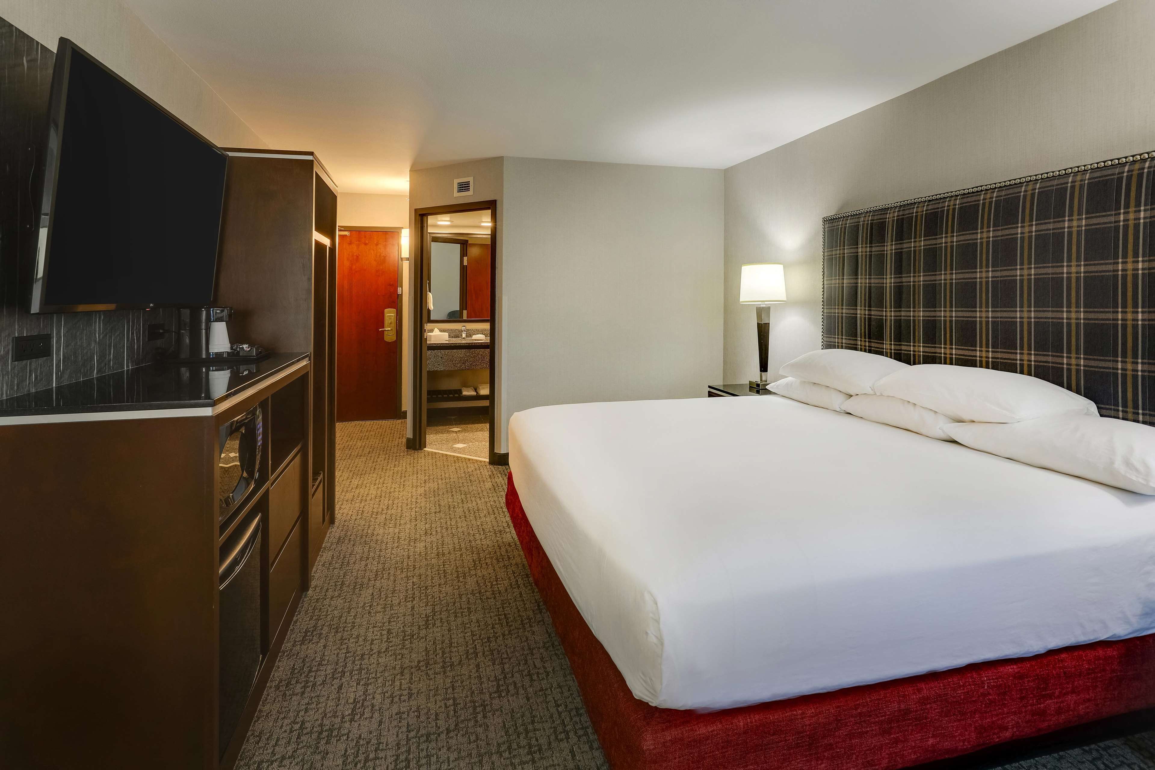 Een hotelkamer met een bed, een televisie, een bureau en een spiegel.