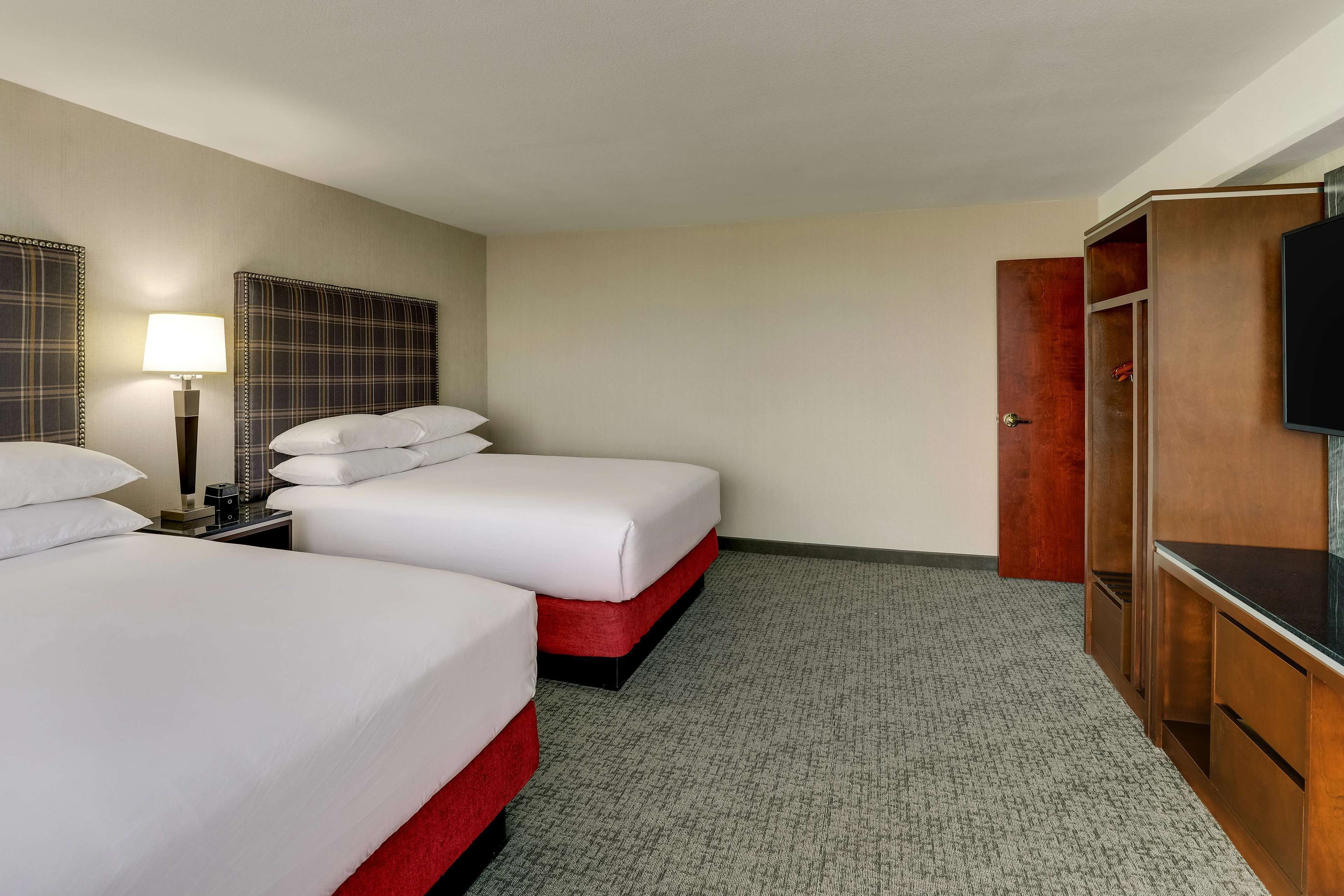 A hotel room with two beds, a TV, a desk, and a wardrobe.