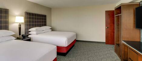 Una habitación de hotel con dos camas, televisión, escritorio y armario.