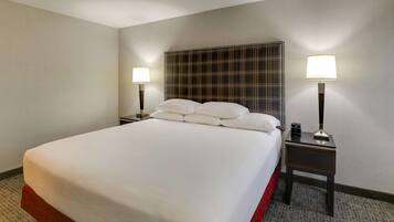Habitación de hotel con una cama grande, dos mesitas de noche con lámparas y un cabecero estampado con un diseño escocés.