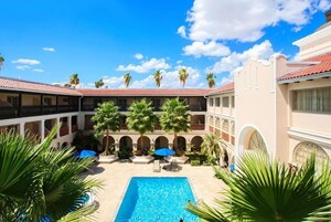 Un patio con piscina, palmeras y un edificio de techo rojo.