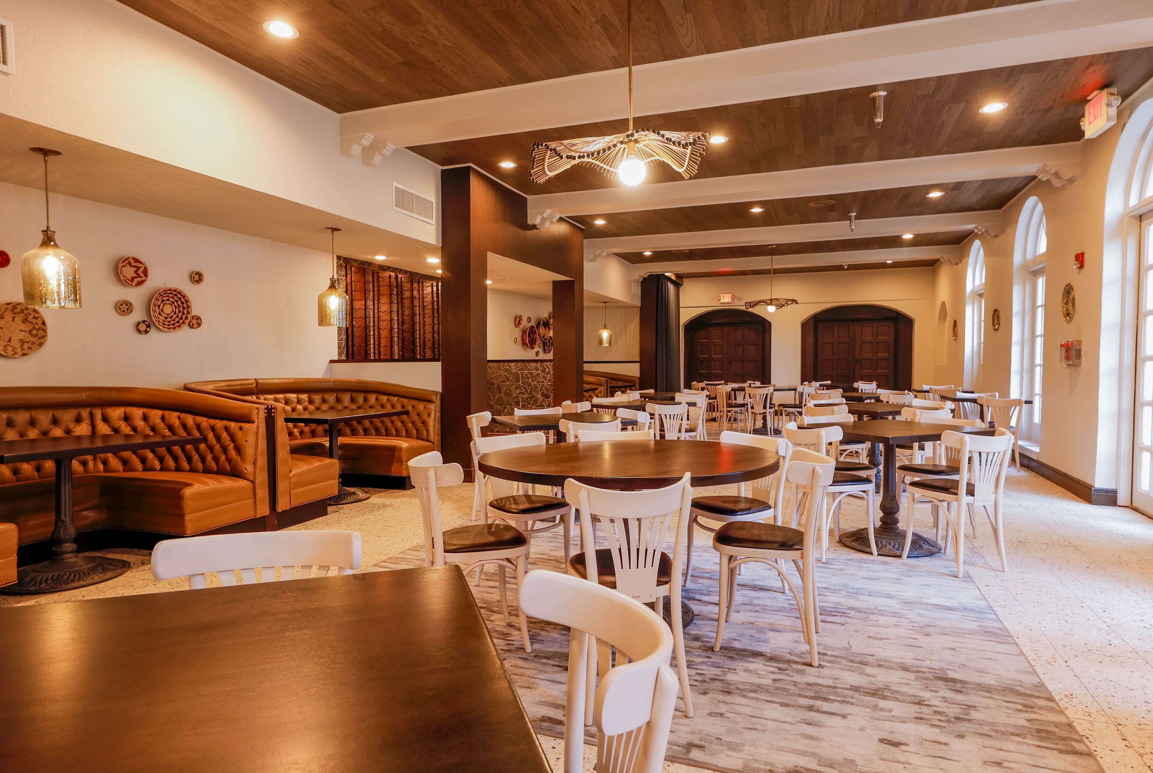 Un restaurante con cabinas de madera, sillas blancas y una mesa de comedor central.