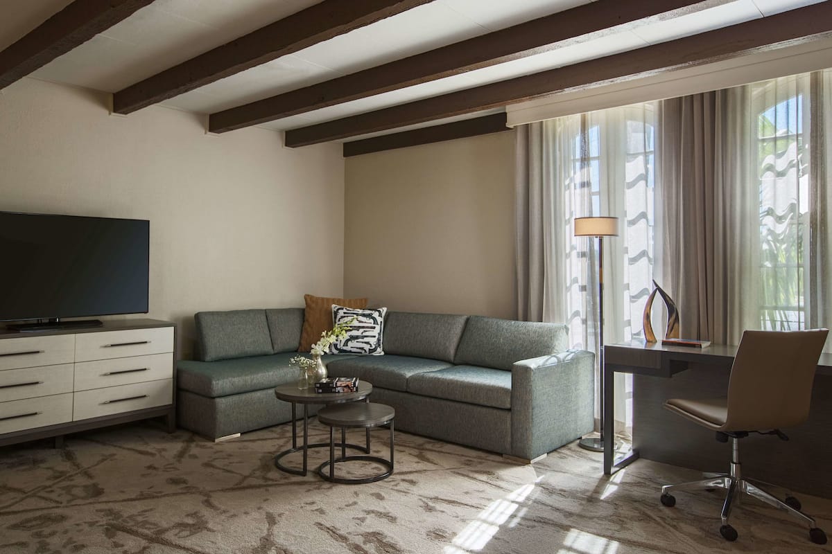 Una sala de estar con sofá, televisión, una mesita y un escritorio con silla.