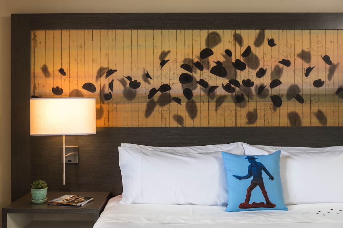 Una habitación de hotel con una cama, una mesita de noche con una lámpara y un panel de madera en la pared.