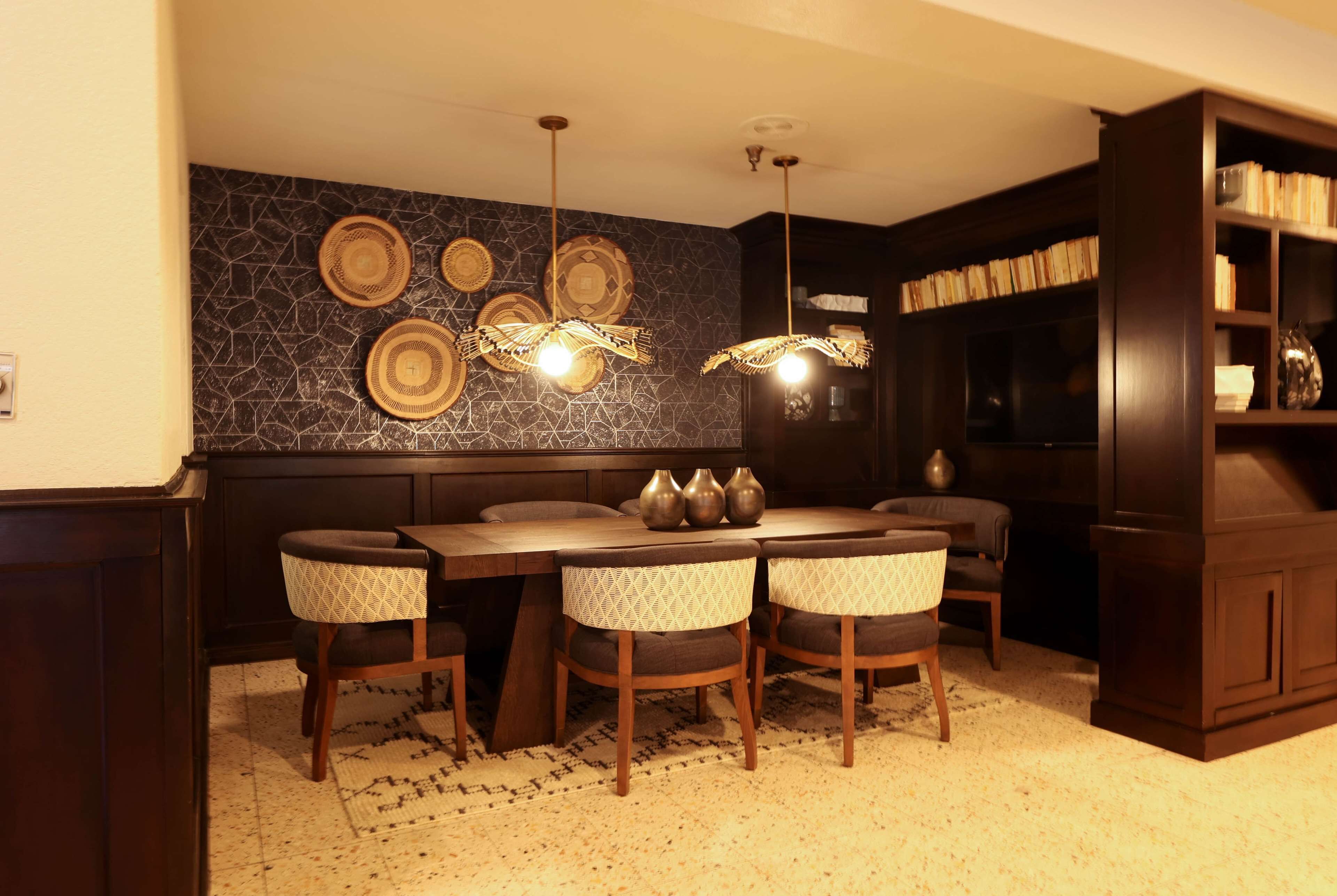 A dining area with a dark wood table and chairs, a patterned rug, and a wall with decorative plates.