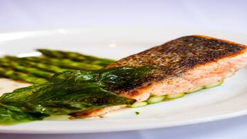 A plate with a piece of salmon, asparagus, and a leafy green.