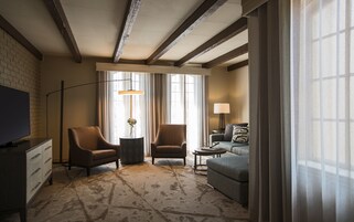 Una habitación de hotel con televisión, dos sillones, un sofá, una mesita y una lámpara.
