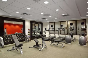 A gym with treadmills, elliptical machines, and weight benches.