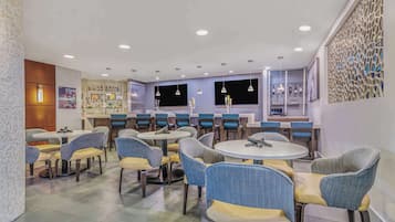 Um restaurante moderno com mesas e cadeiras redondas, uma área de bar e uma parede decorativa.