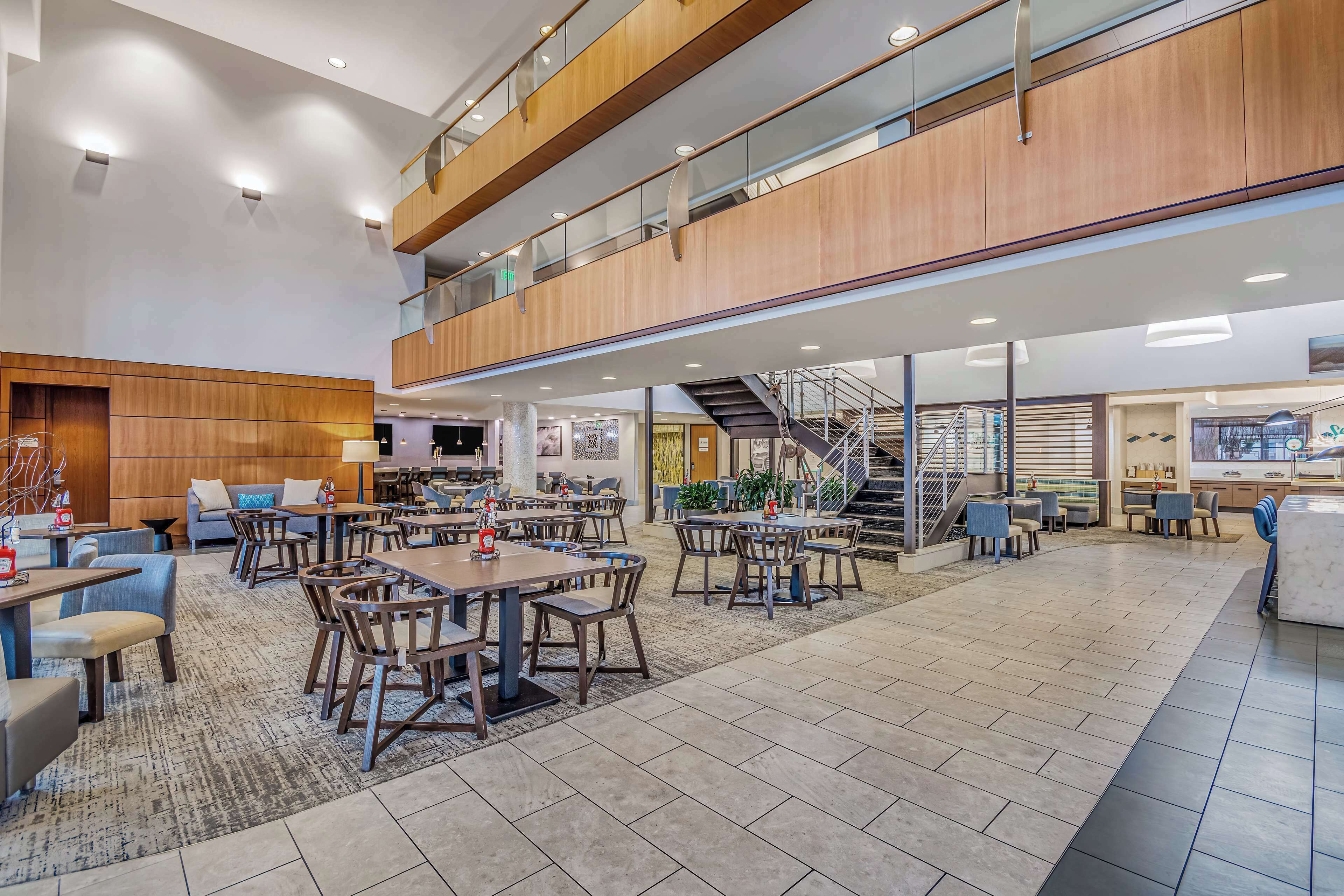 A spacious indoor area with multiple dining tables and chairs, a staircase, and a view of the lower level.