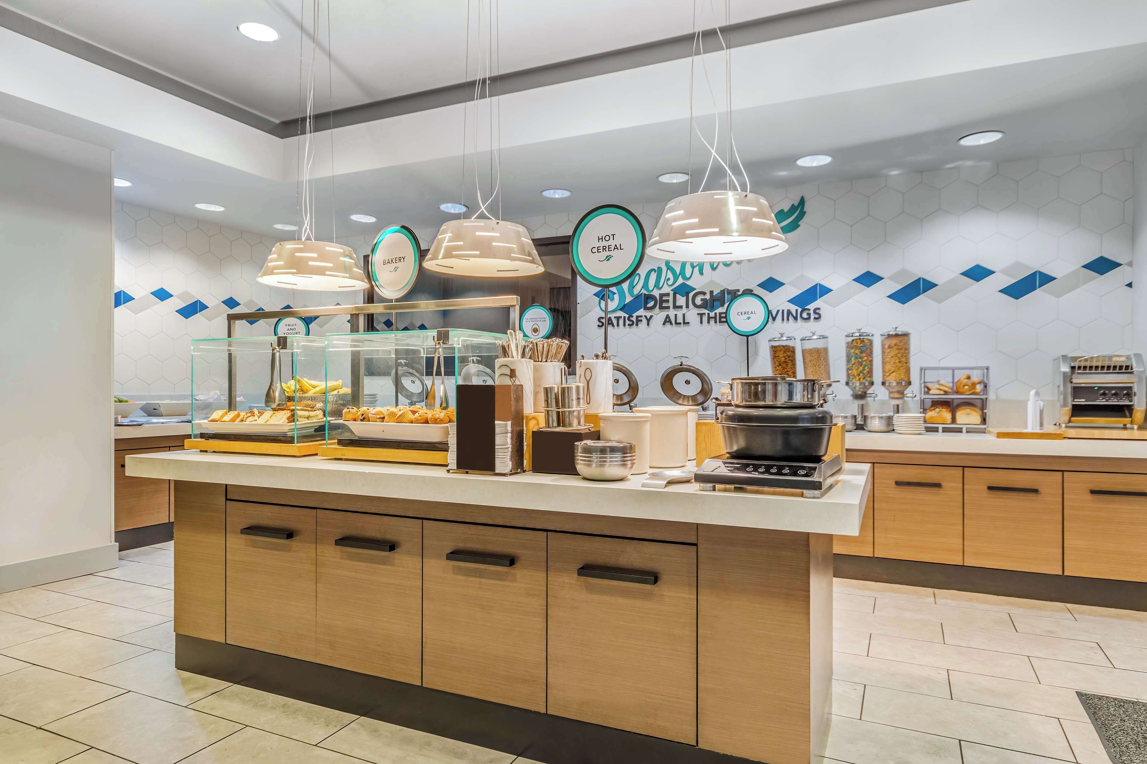 A breakfast bar with a variety of food items and a sign indicating 'Hot Cereal' and 'Bakery'.