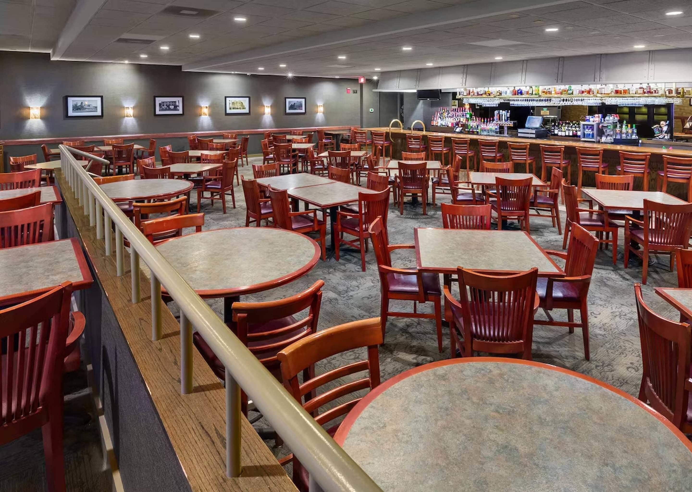 Un restaurant doté de nombreuses tables et chaises, d’un bar et de tableaux encadrés aux murs.