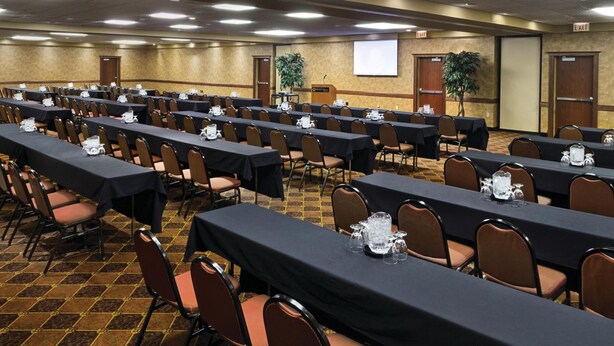 A conference room with rows of tables and chairs, equipped with nameplates and water pitchers.