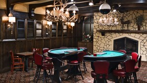A casino with multiple blackjack tables, red chairs, and a stone fireplace.