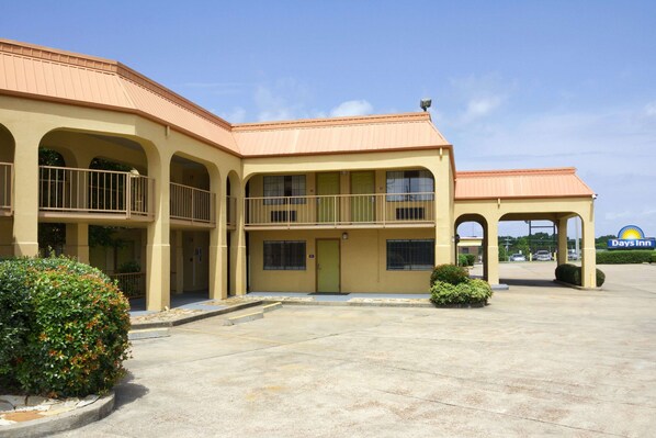 Stylish hotel with a central entrance and two wings, featuring a flat roof and balconies with metal railings.