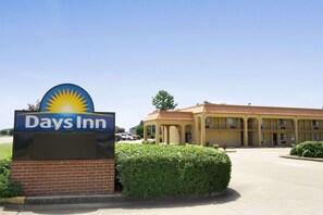 Welcome to Days Inn, a hotel with a prominent sign and a modern building surrounded by well-manicured hedges.