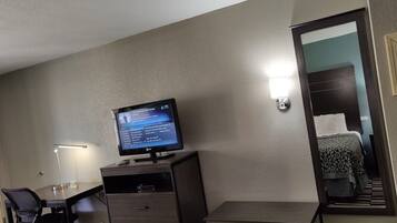 A hotel room with a desk, chair, and a television displaying a movie.