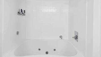 A white bathtub with a showerhead and two faucets.