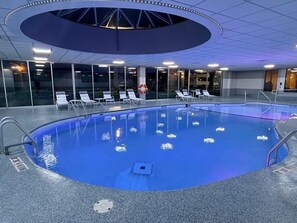 An indoor swimming pool with clear water, surrounded by lounge chairs and a glass wall. - Royle Hotel Milwaukee Airport (Milwaukee)