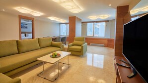 Una sala moderna con sofá, sillones, una mesa de centro y un televisor de pantalla plana.