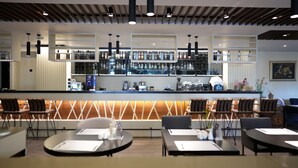 Un bar moderno con una variedad de botellas de licores, una máquina de café y diferentes opciones de asientos.