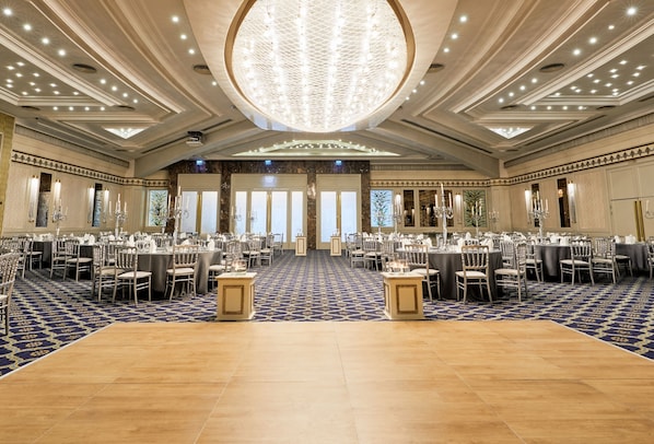 A spacious banquet hall with a high ceiling, chandeliers, and a patterned carpet.