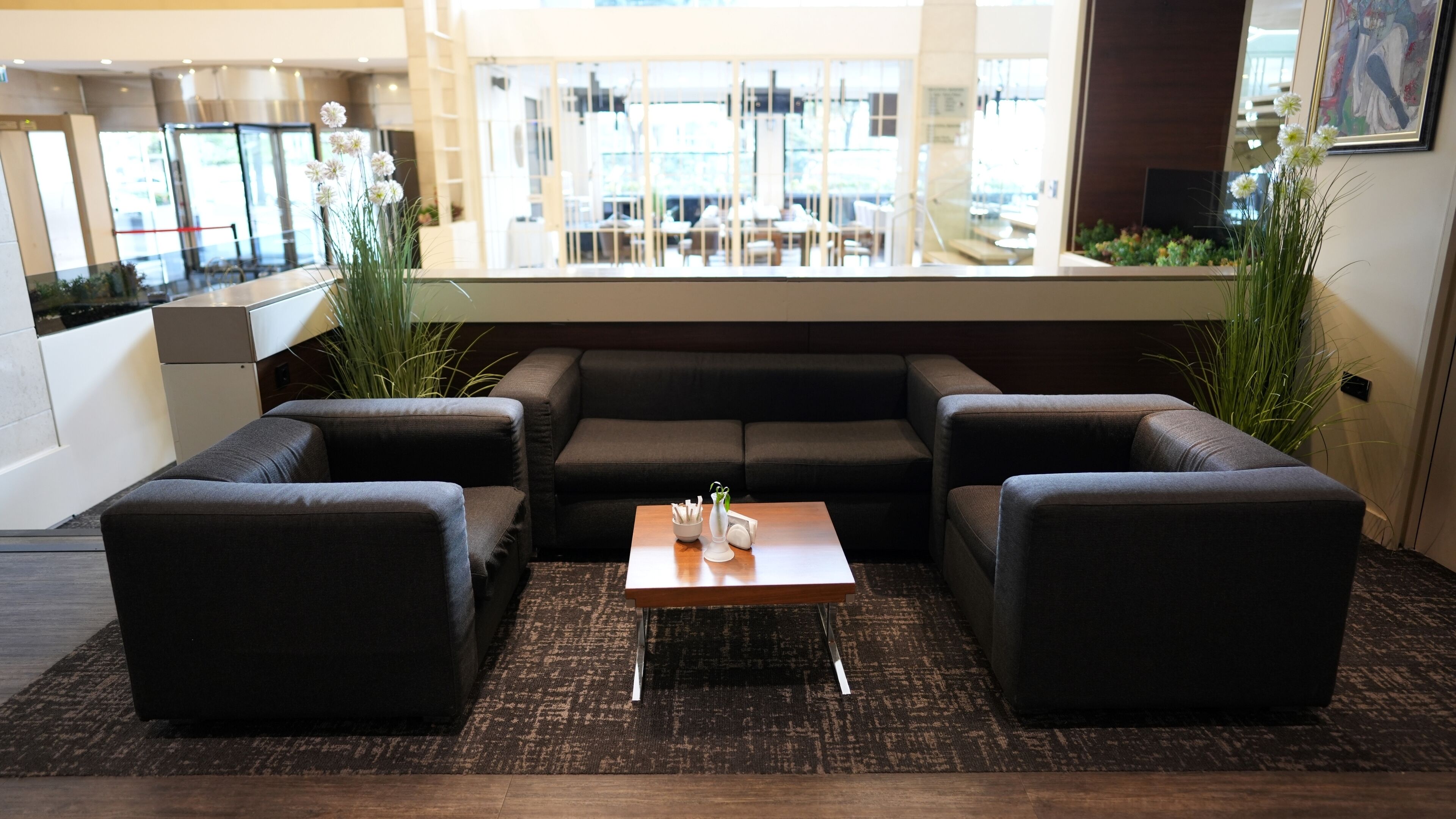 A modern lounge area with a sofa set, a coffee table, and a view of the lobby.