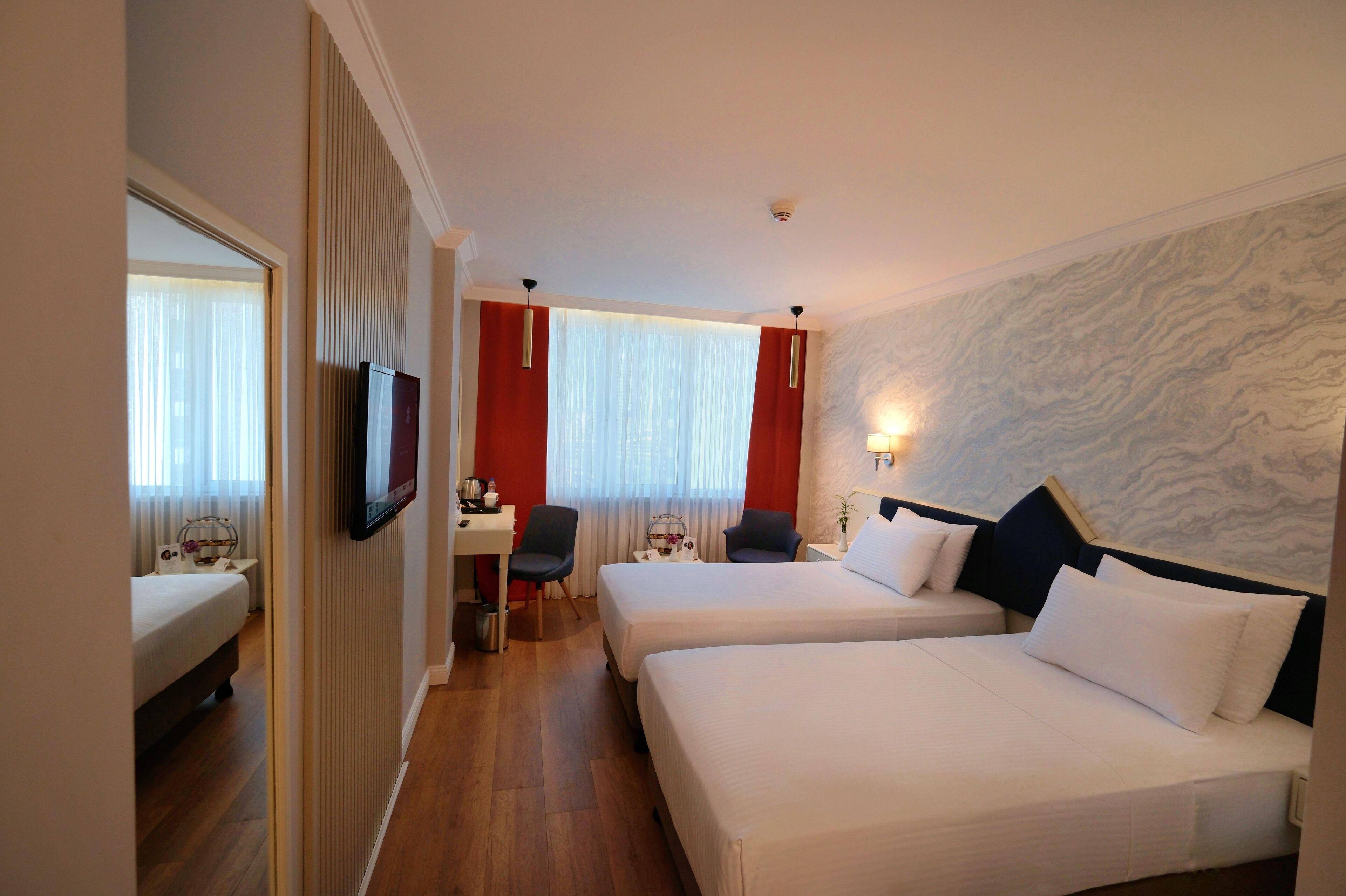 A hotel room with two beds, a desk, and a television.