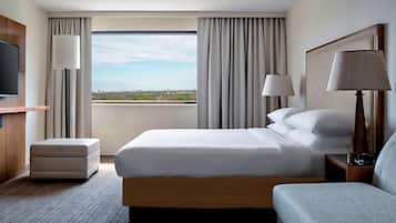 Habitación de hotel con una cama grande, televisor, escritorio y vistas a la ciudad.