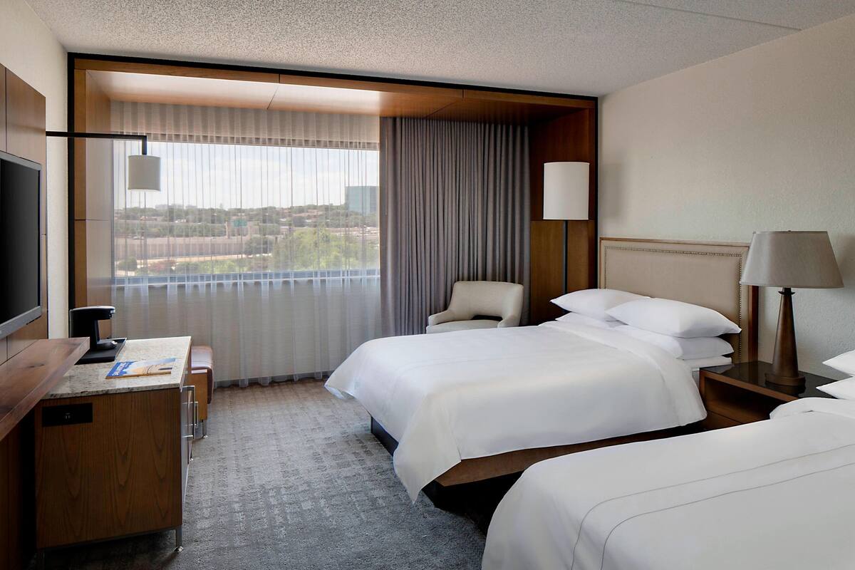 Una habitación de hotel con una cama grande, un escritorio, una silla y un televisor.